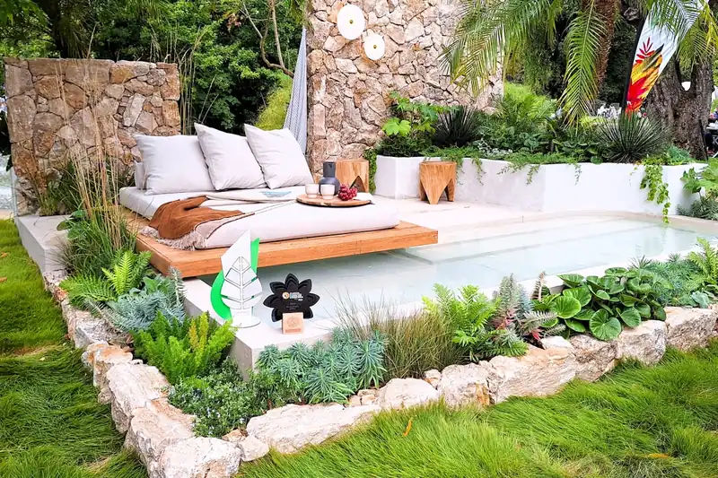 Eine Doppelliege als zentrales Element einer stilvoll eingerichteten Terrasse mit Pflanzen.