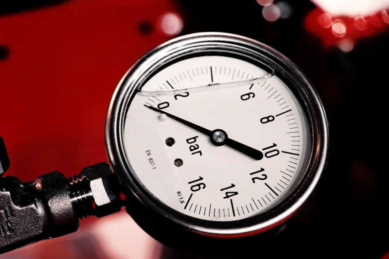 Nahaufnahme des Manometers und Ventils eines Druckluftkompressors, Detail der Leistungskomponenten.