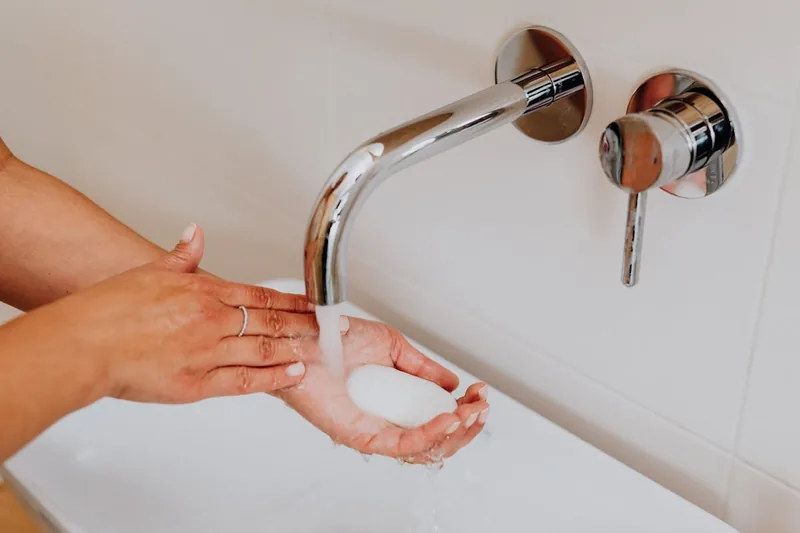 Eine Person wäscht sich die Hände unter warmem Wasser, bereitgestellt durch einen Durchlauferhitzer.