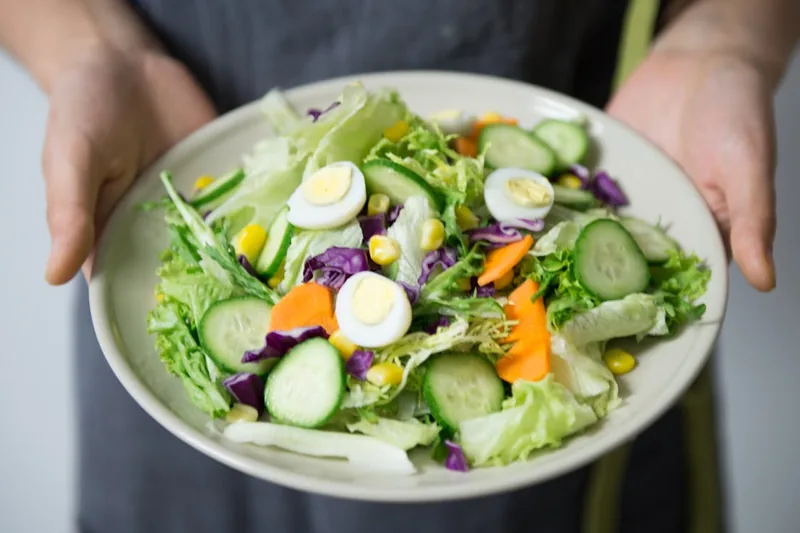 Ein bunter Salat mit perfekt geschnittenen Eierscheiben, angerichtet auf einem Teller in einer ansprechenden Küchenszene.