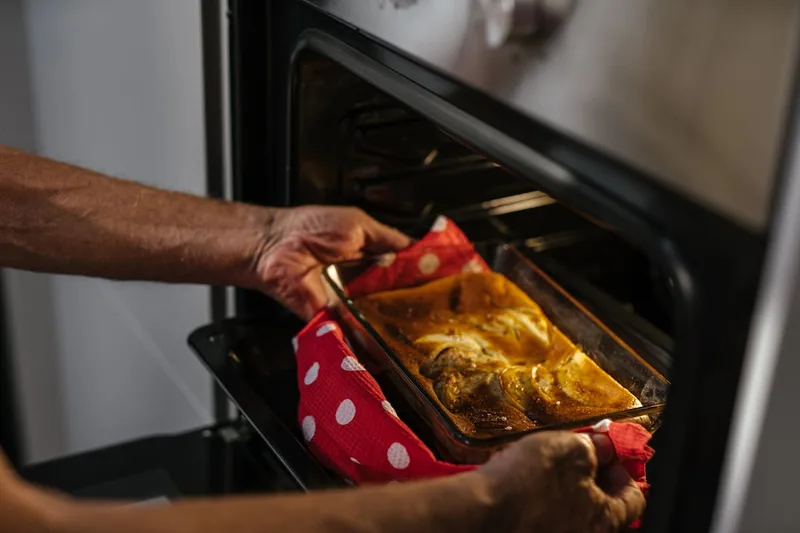 Eine Person schiebt ein Backblech mit Teig in einen Einbaubackofen, bereit für das perfekte Backergebnis.