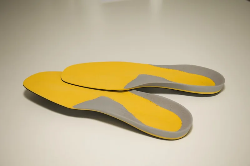 Ein Paar neuwertiger ergonomischer Einlegesohlen, klar und detailliert vor neutralem Hintergrund.