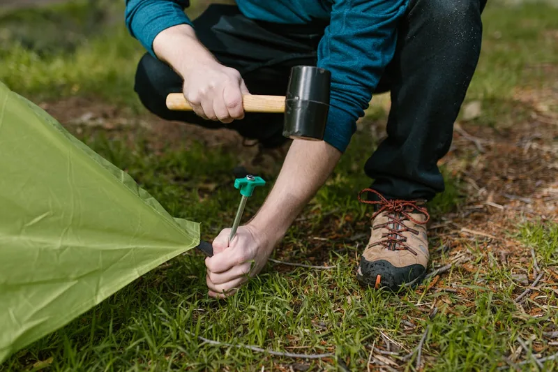 Eine Person baut ein ultraleichtes Einmannzelt in einer natürlichen Outdoor-Umgebung auf.