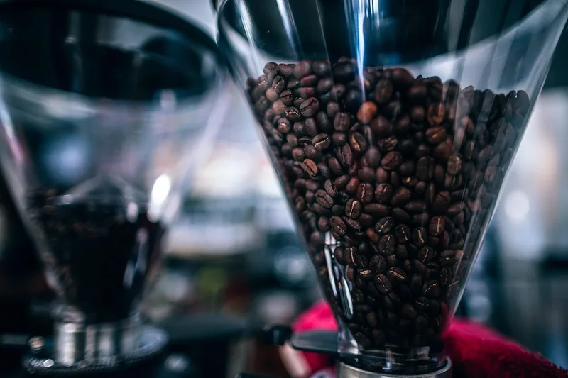 Frisch gebrühter Kaffee mit dichter Crema, umgeben von Kaffeebohnen auf einem Küchentisch.