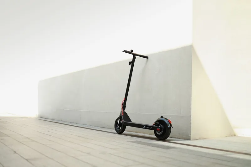 Ein moderner Elektro-Scooter steht freigestellt auf einem hellen Hintergrund, bereit zum Einsatz.