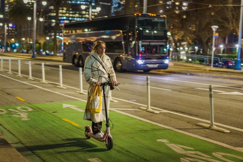 Eine Person fährt mit einem Elektro-Scooter auf einem Radweg in der Stadt, im Alltagseinsatz.