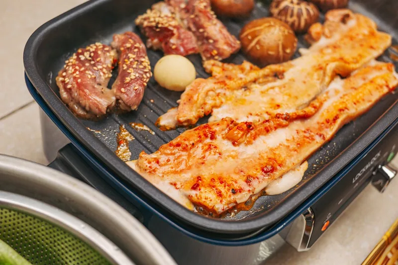 Gemütlicher Balkon mit gedecktem Tisch und Elektrogrill für ein entspanntes Outdoor-Essen.