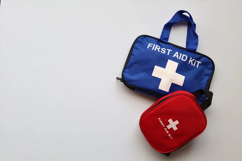 Eine Person versorgt eine kleine Wunde mit einem Pflaster aus einem Erste-Hilfe-Koffer.