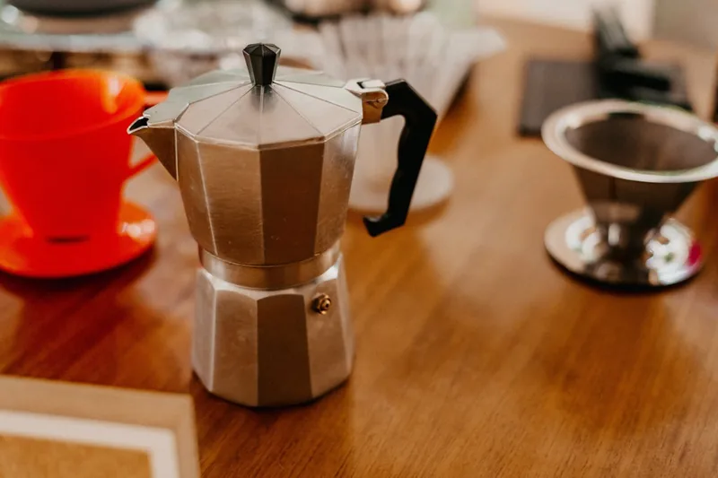 Ein glänzender Edelstahl Espressokocher, klar vor neutralem Hintergrund fotografiert.