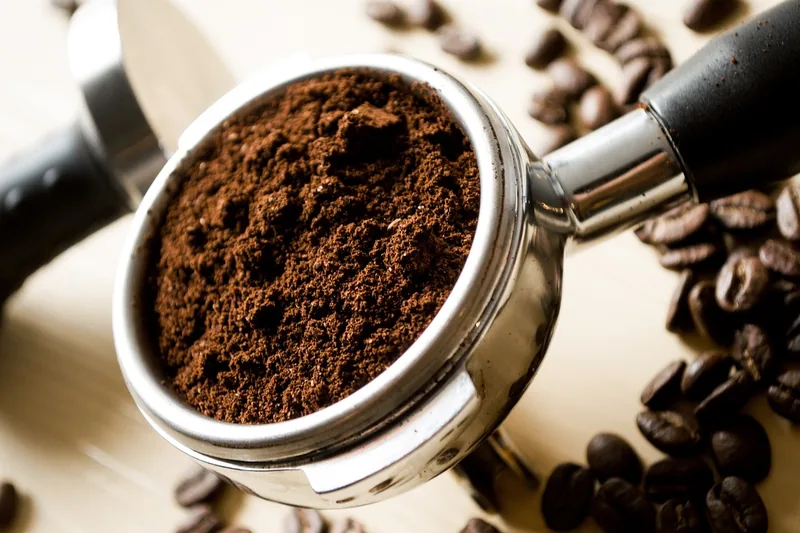 Nahaufnahme des Siebträgers einer Espressomaschine mit gemahlenem Kaffee, zeigt Textur und Verarbeitung.