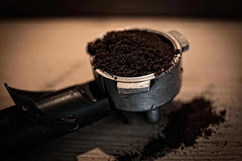 Eine Person bedient eine Siebträgermaschine, um Espresso zuzubereiten, Fokus auf die Zubereitung.