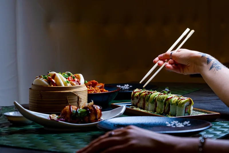 Ein stilvoll gedeckter Tisch im asiatischen Ambiente, mit appetitlichen Gerichten und Essstäbchen Sets für Gäste.