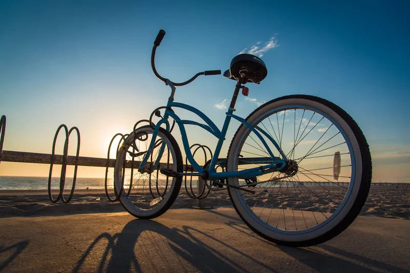 Ein stilvolles Cruiser Fahrrad steht geparkt an einer Strandpromenade bei Sonnenuntergang, idyllische Szene.