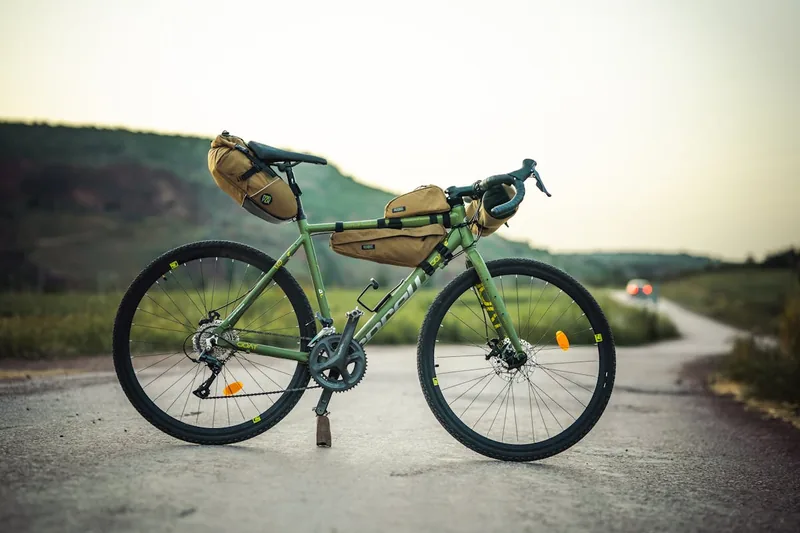 Eine Person befestigt eine Fahrrad-Rahmentasche mit Klettverschlüssen sicher am Rahmen eines Mountainbikes.