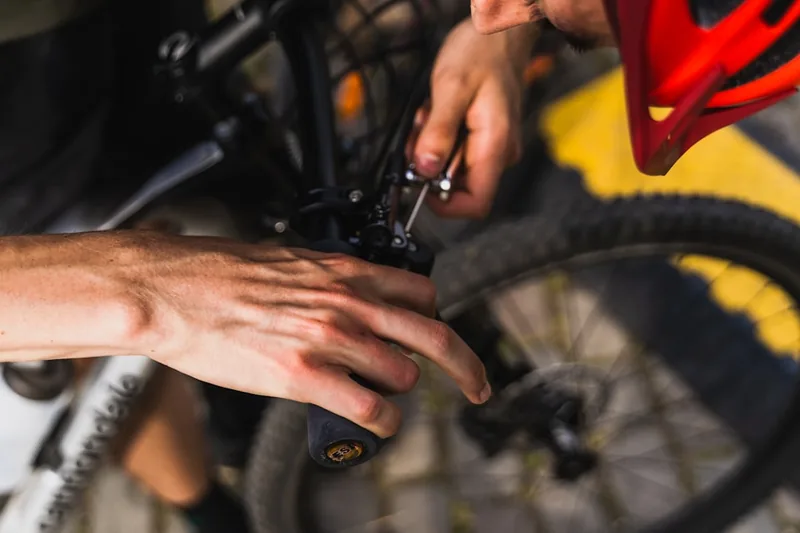 Hände betätigen einen Fahrrad Schnellspanner am Laufrad, um es sicher am Fahrradrahmen zu befestigen.
