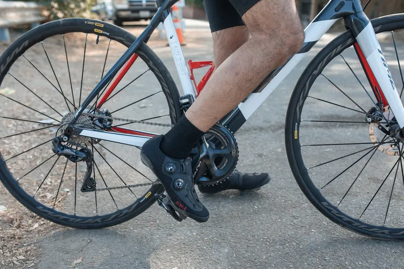 Eine Person zieht einen Fahrrad-Überschuh über den Radschuh, um die Füße zu schützen.
