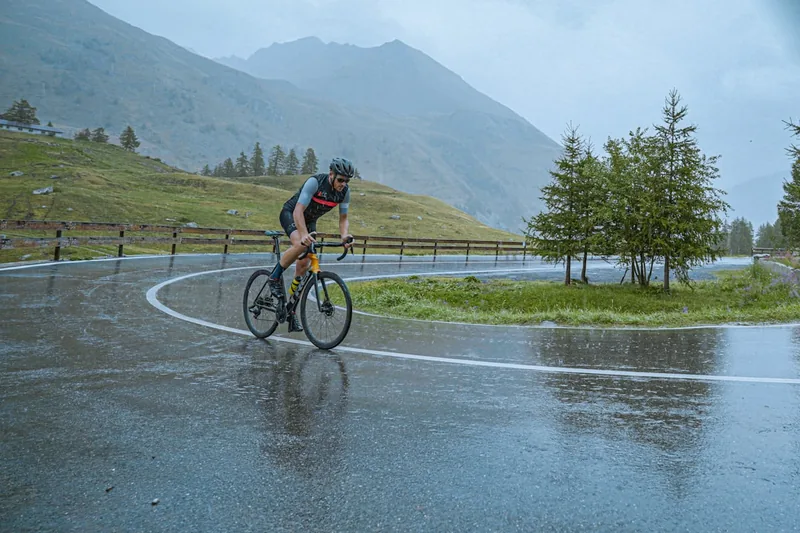 Ein Radfahrer auf einem Rennrad bei regnerischem Wetter, die Füße durch Überschuhe geschützt.