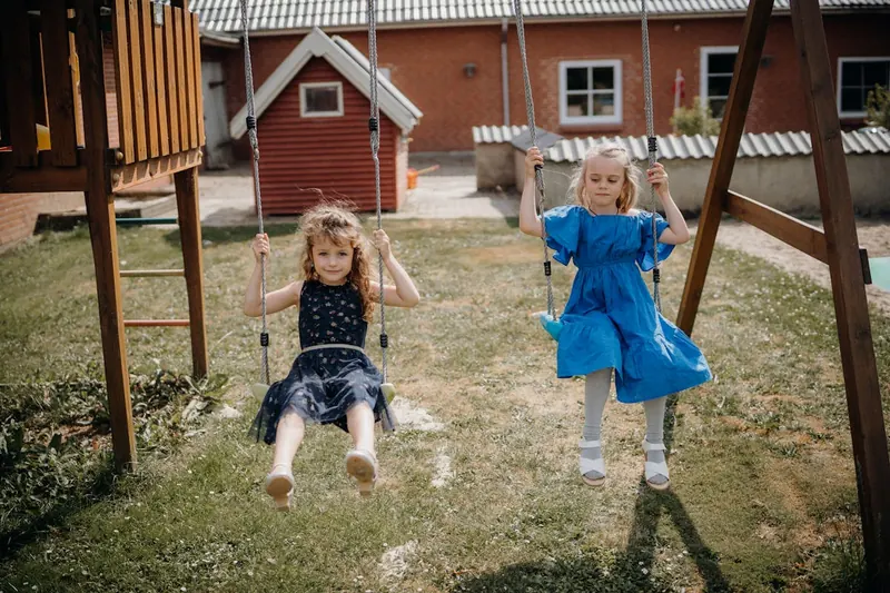 Ein Kind in Bewegung auf einem Spielturm, lachend beim Herunterrutschen der Wellenrutsche im Garten.