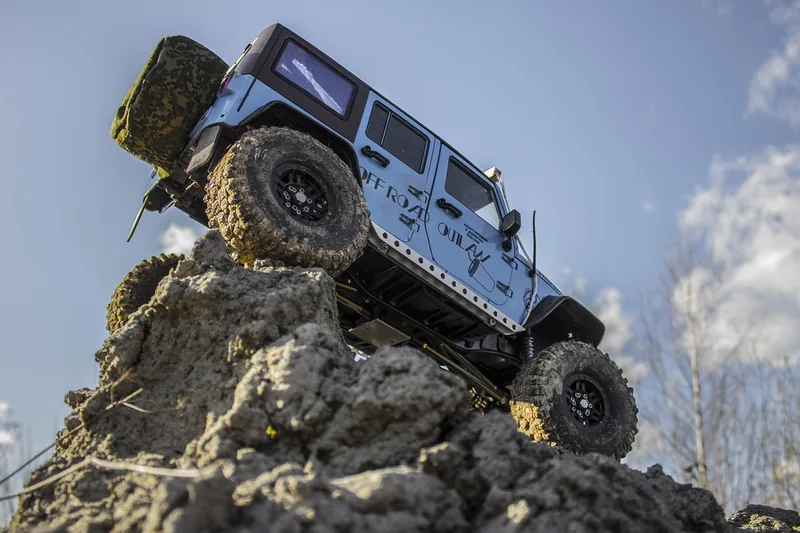 Eine Person steuert ein ferngesteuertes Rennauto draußen auf einem staubigen Offroad-Parcours.
