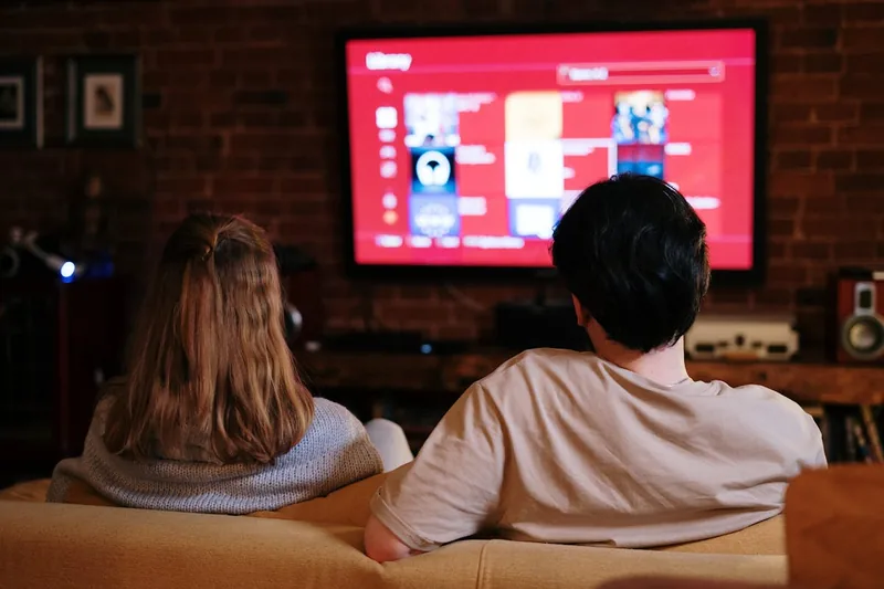 Gemütliche Wohnzimmer-Szene mit einem großen 55-Zoll-4K-Fernseher als Mittelpunkt des Heimkino-Erlebnisses.