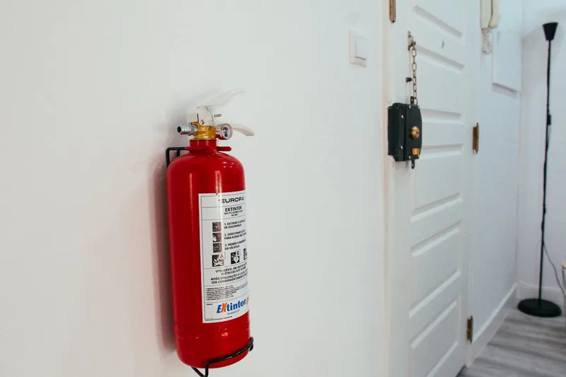 Ein Feuerlöscher in einem modernen Büroflur, sichtbar an einer Wandhalterung neben einem Notausgang.