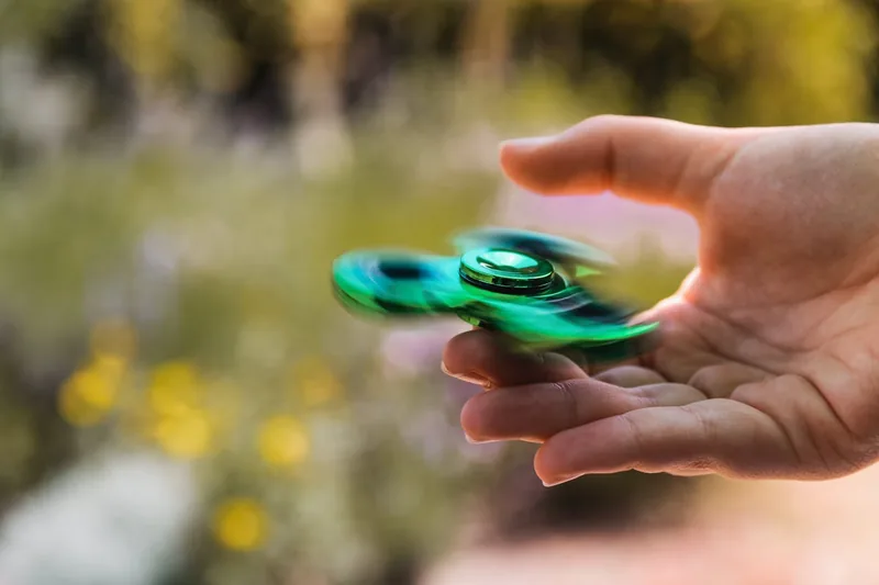 Eine Hand hält und dreht einen Fidget Spinner, um Stress abzubauen.