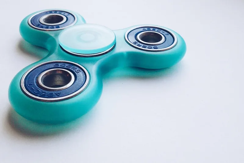 Ein aufgeräumter Schreibtisch mit einem Fidget Spinner als Teil der Dekoration.