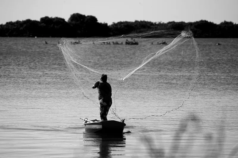 Ein Angler hält stolz einen großen Fisch in den Händen, mit einem ruhigen See im Hintergrund, symbolisiert erfolgreiches Angeln.