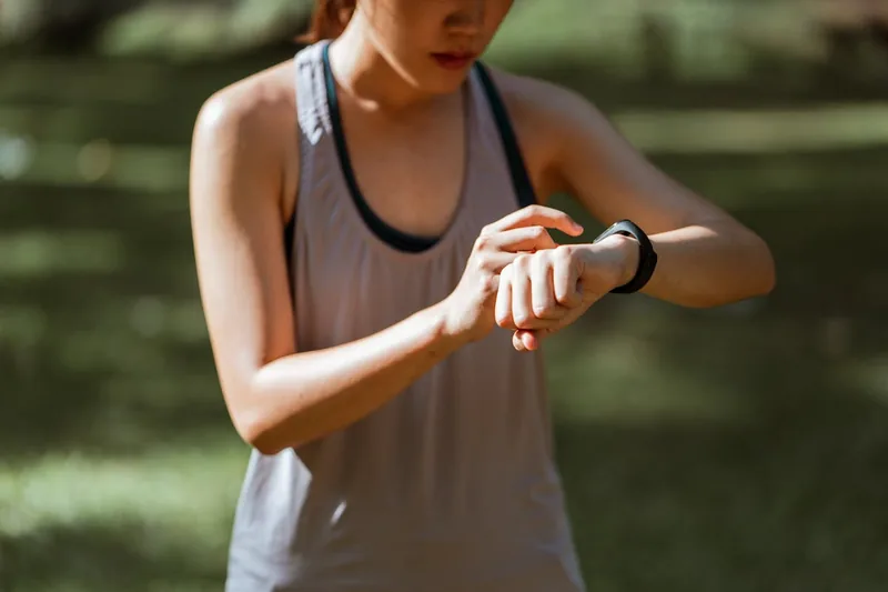 Eine Person trägt ein Fitness-Armband während des Joggens, sichtbar am Handgelenk in Aktion.
