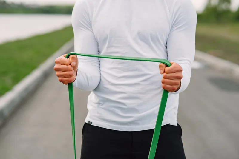 Eine Person dehnt sich mit einem langen Fitnessband, um Muskeln zu stärken.