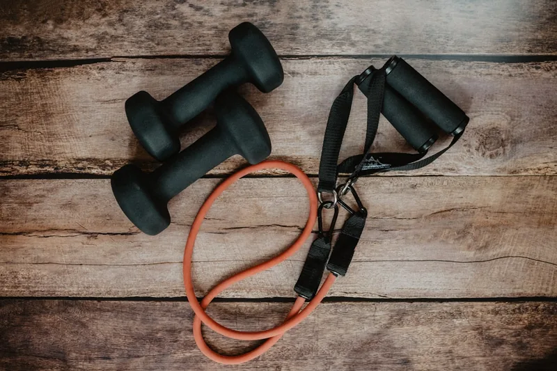 Ein aufgeräumtes Home-Gym mit einer Yogamatte, Hanteln und Fitnessbändern, bereit für die tägliche Routine.