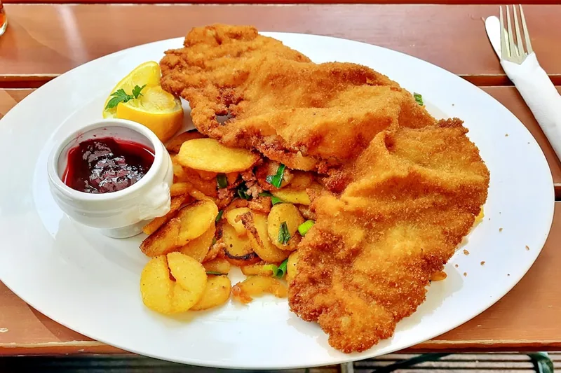 Ein fertig zubereitetes, zartes Schnitzel auf einem Teller in einer ansprechenden Küchenszene.