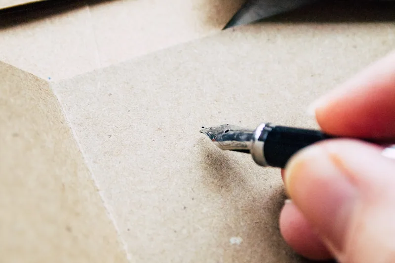 Eine Hand schreibt mit einem Füllfederhalter elegant auf Papier, Fokus auf die Schreibbewegung.