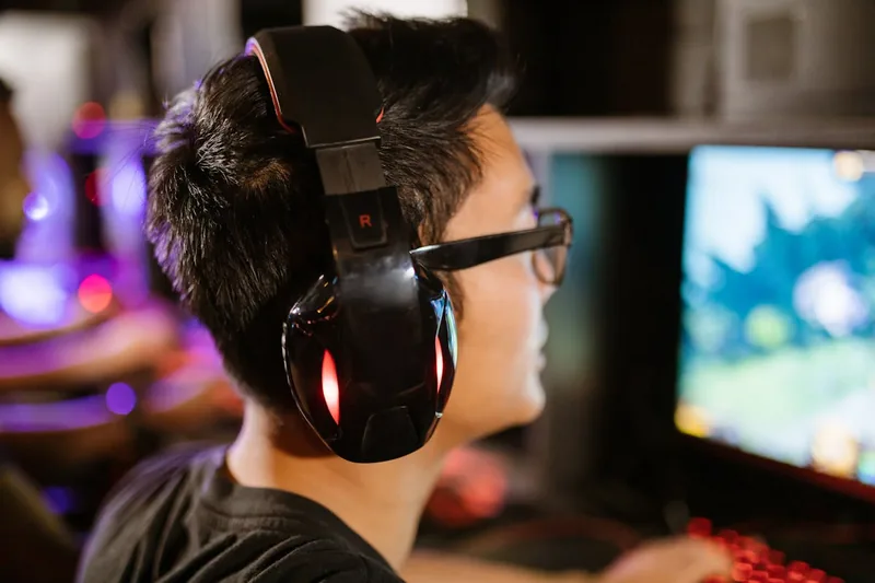 Eine Person trägt ein Gaming Headset und konzentriert sich auf das Spielen am Computer.