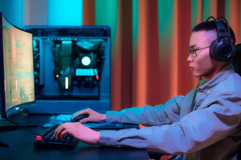 Gamer spielt aktiv an einem Gaming-PC mit Tastatur und Maus, immersive Gaming-Szene.