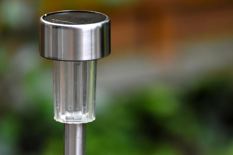 Eine elegante Solar-Gartenleuchte im Vordergrund, Design und Solarpaneel klar erkennbar, weißer Hintergrund.