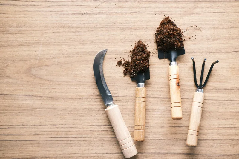 Eine moderne Gartenkralle aus Metall und Holz, sauber und neu, im Vordergrund präsentiert.