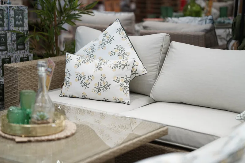 Ein elegantes, modernes Gartensofa aus Polyrattan, frontal auf neutralem Hintergrund.