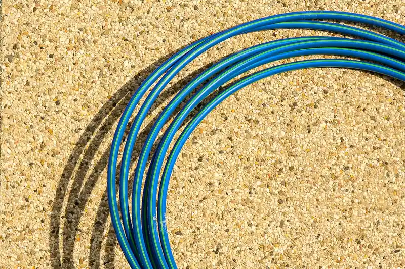Nahaufnahme der Materialtextur eines Gartenschlauchs und eines hochwertigen Anschlussstücks, Fokus auf Qualität.