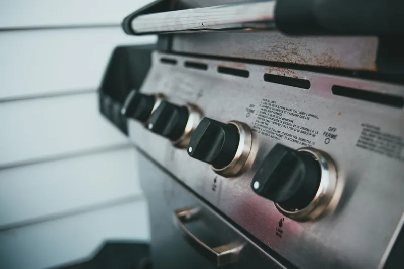 Detailaufnahme des Bedienfelds eines Gasgrills mit präzisen Reglern und Temperaturanzeige aus Edelstahl.