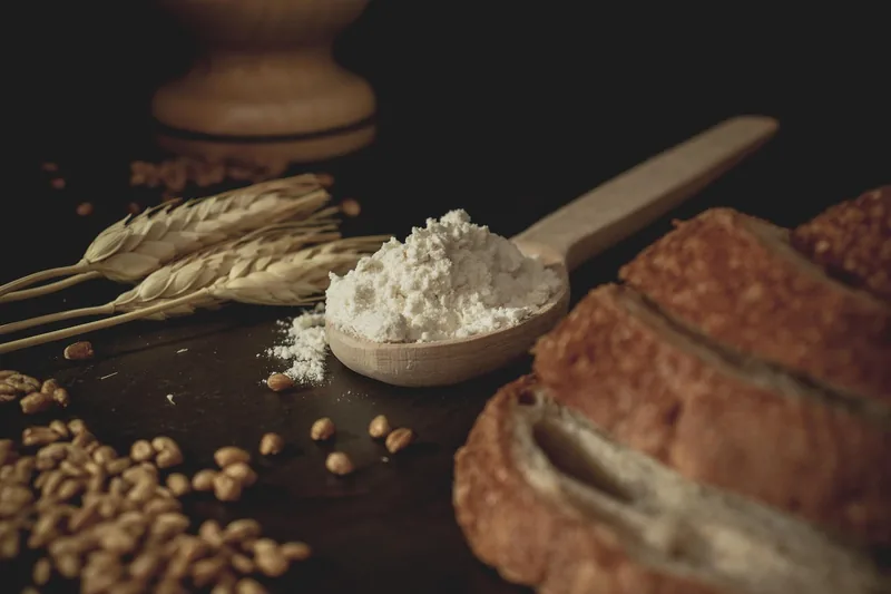 Tischszene mit frisch gebackenem Brot, Mehl und Getreide, Ausdruck gesunden Genusses zu Hause.