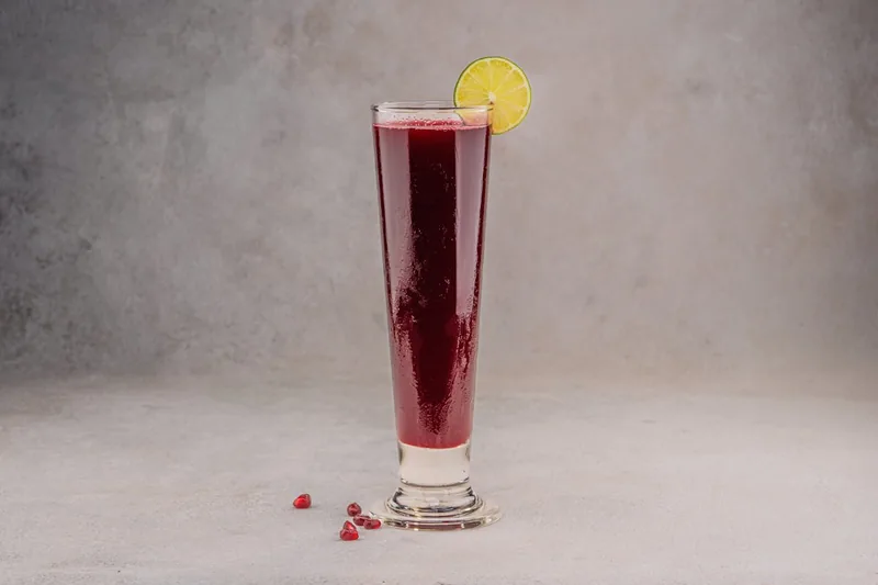 Nahaufnahme von frischem, leuchtend rotem Granatapfelsaft in einem Glas, zeigt die Qualität.
