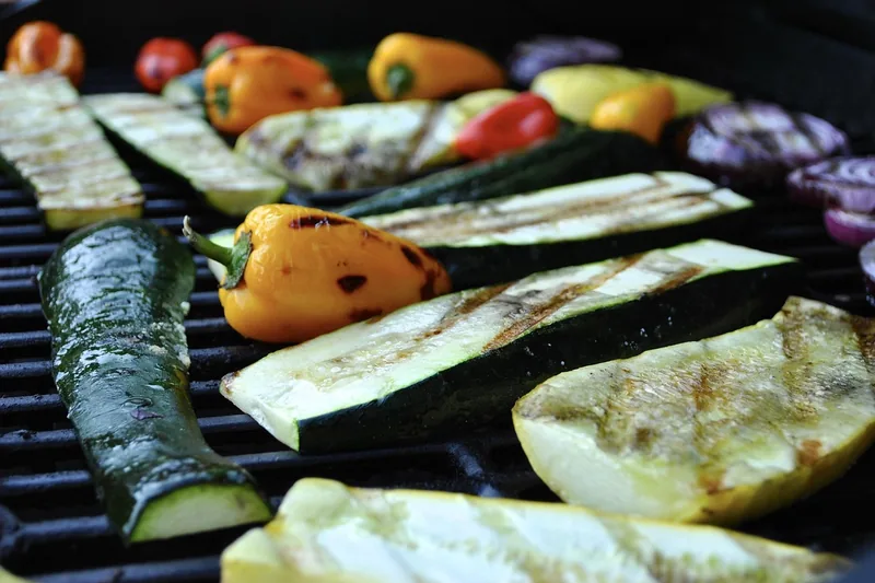 Gemütliche Szene eines gedeckten Tisches im Freien mit appetitlichem Grillgut, das Ambiente betonend.