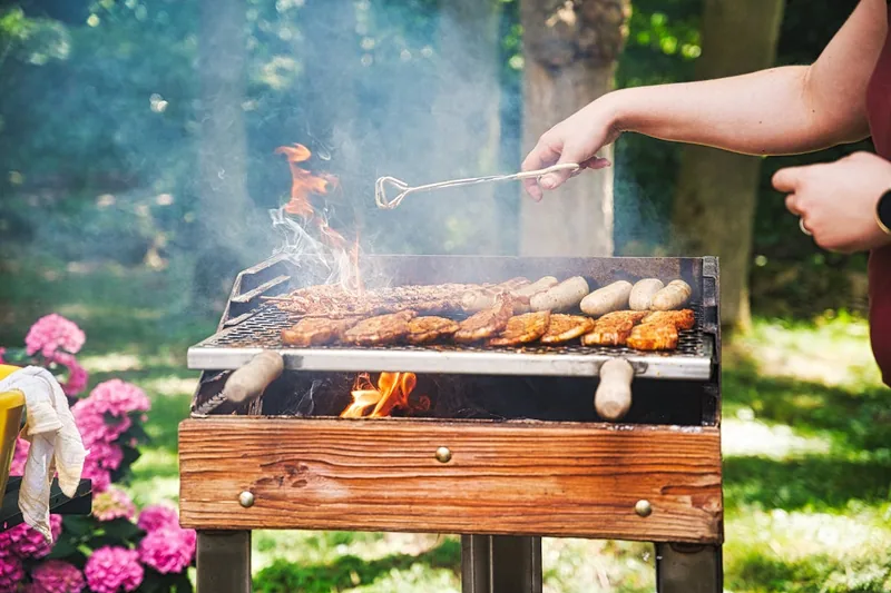 Entspannte Grillabend-Szene im Garten mit Essen und Grillrostheber bereit zum Einsatz.