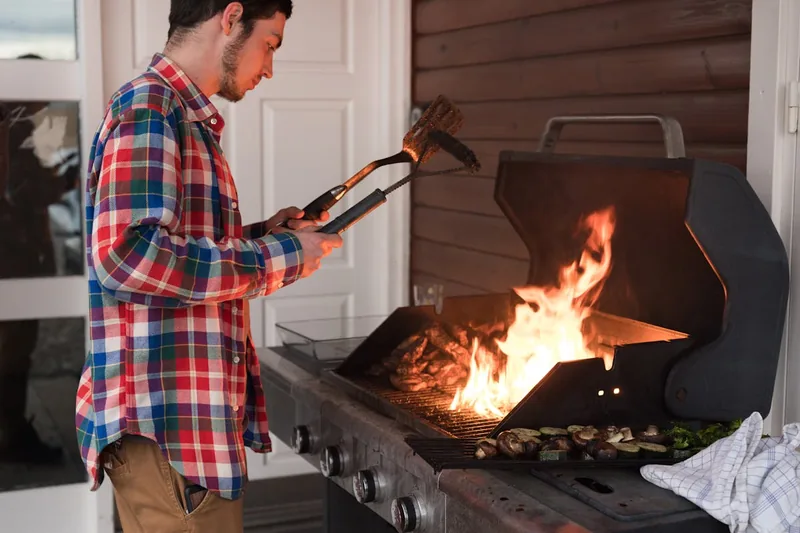 Person wendet Grillgut mit einer Scheren-Grillzange an.