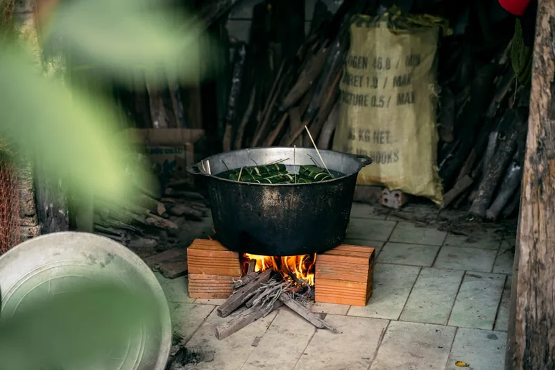 Eine Person rührt mit einem langen Löffel dampfendes Gulasch in einer Gulaschkanone bei einem Event um.
