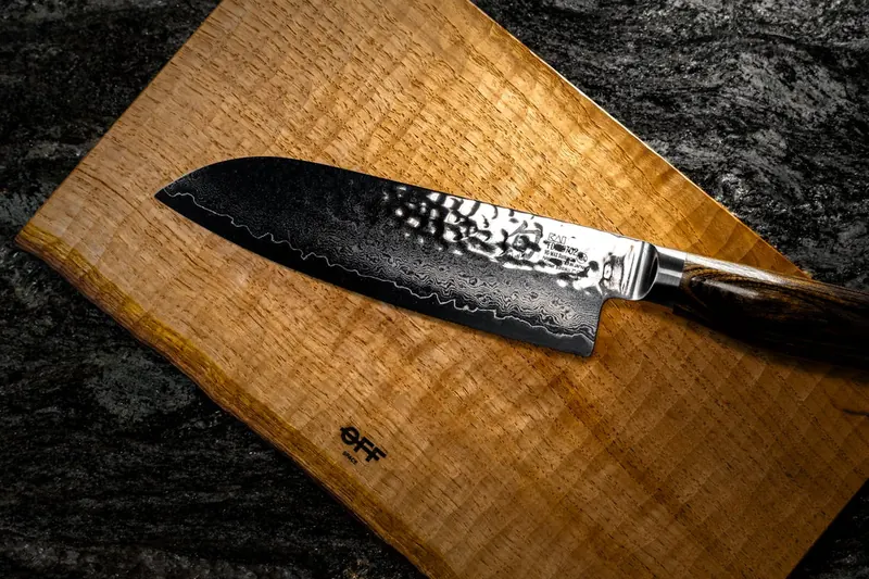 Ein hochwertiges Gyuto Messer mit schlanker Klinge und dunklem Griff, perfekt für präzises Schneiden.