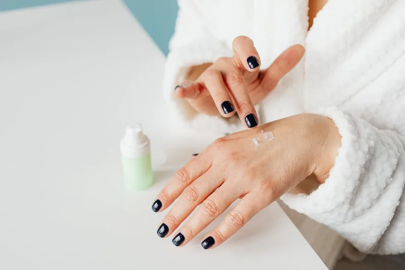 Eine Person trägt sanft ein Handpeeling auf ihre Hände auf, wobei die Anwendung im Fokus steht.