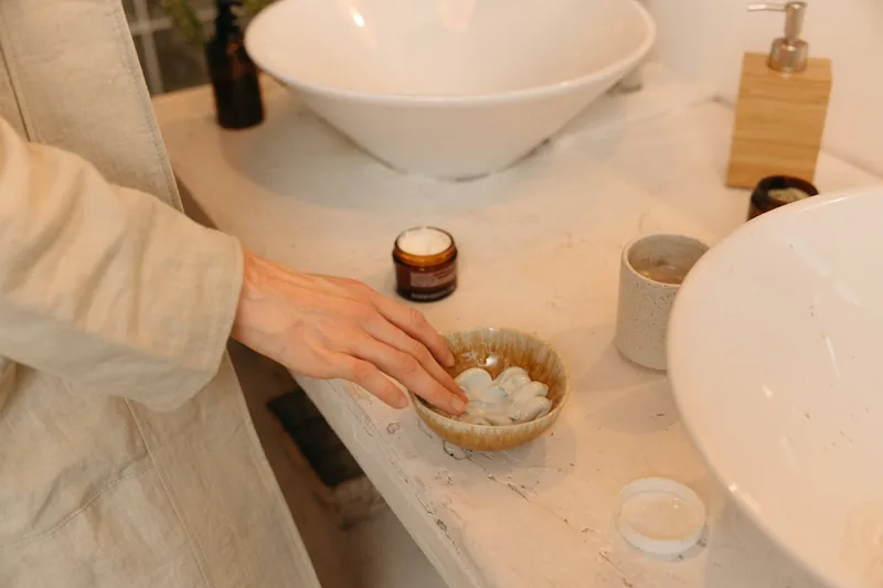 Eine Wellness-Szene im Badezimmer mit gepflegten Händen, umgeben von Handpflegeprodukten und Kerzen.