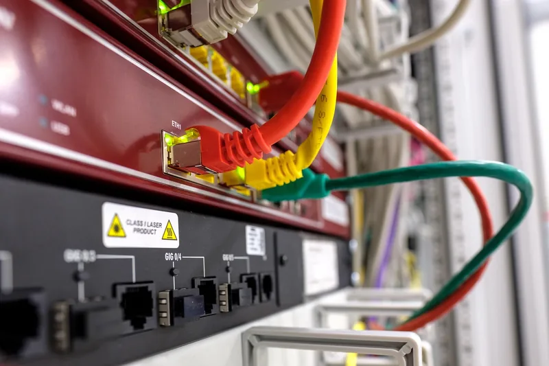 Detailansicht der Rückseite einer Hardware-Firewall mit verschiedenen beleuchteten Netzwerkanschlüssen.